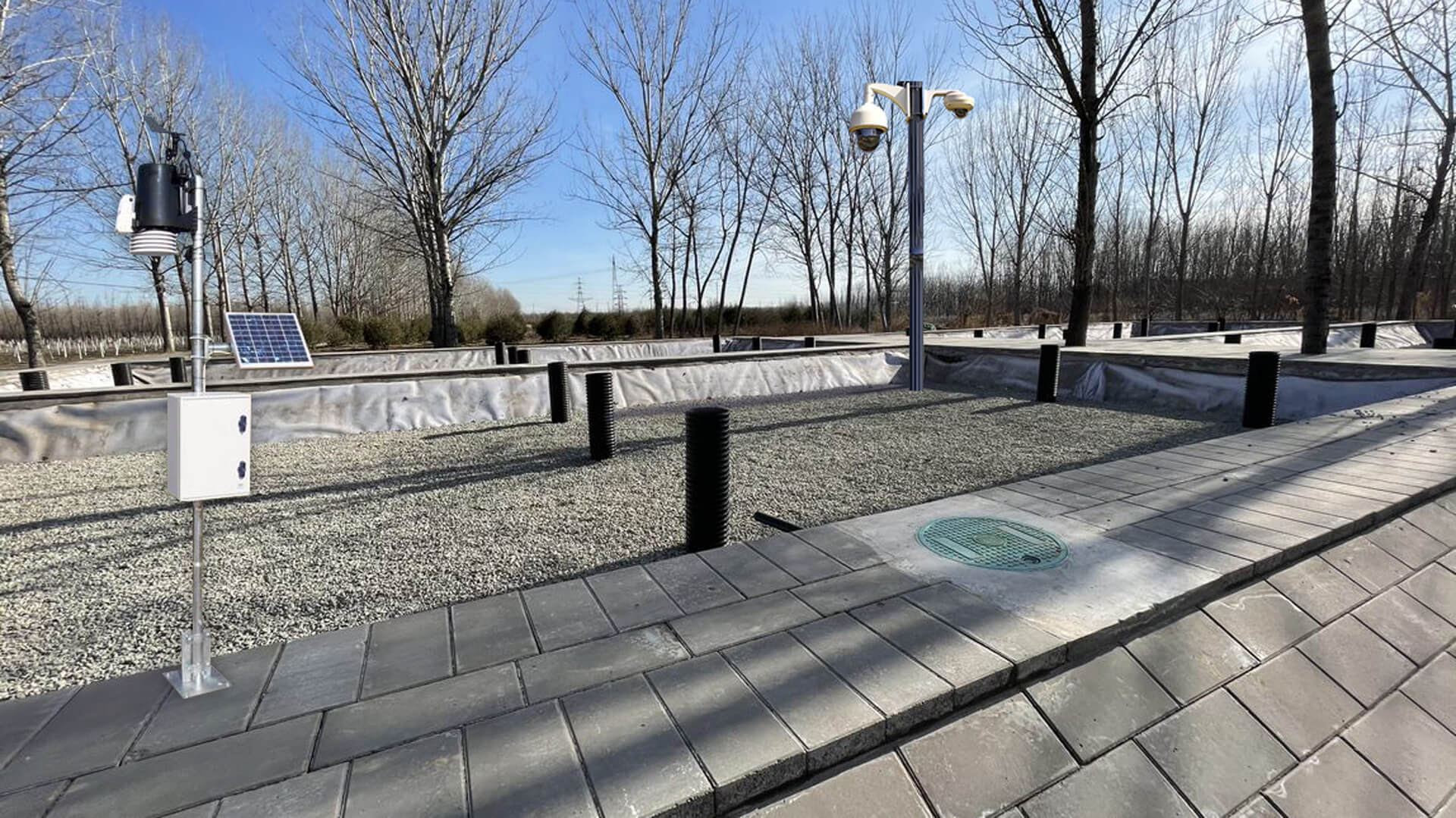 A monitored wetland area with camera and sensor poles, a solar panel and a data cabinet
